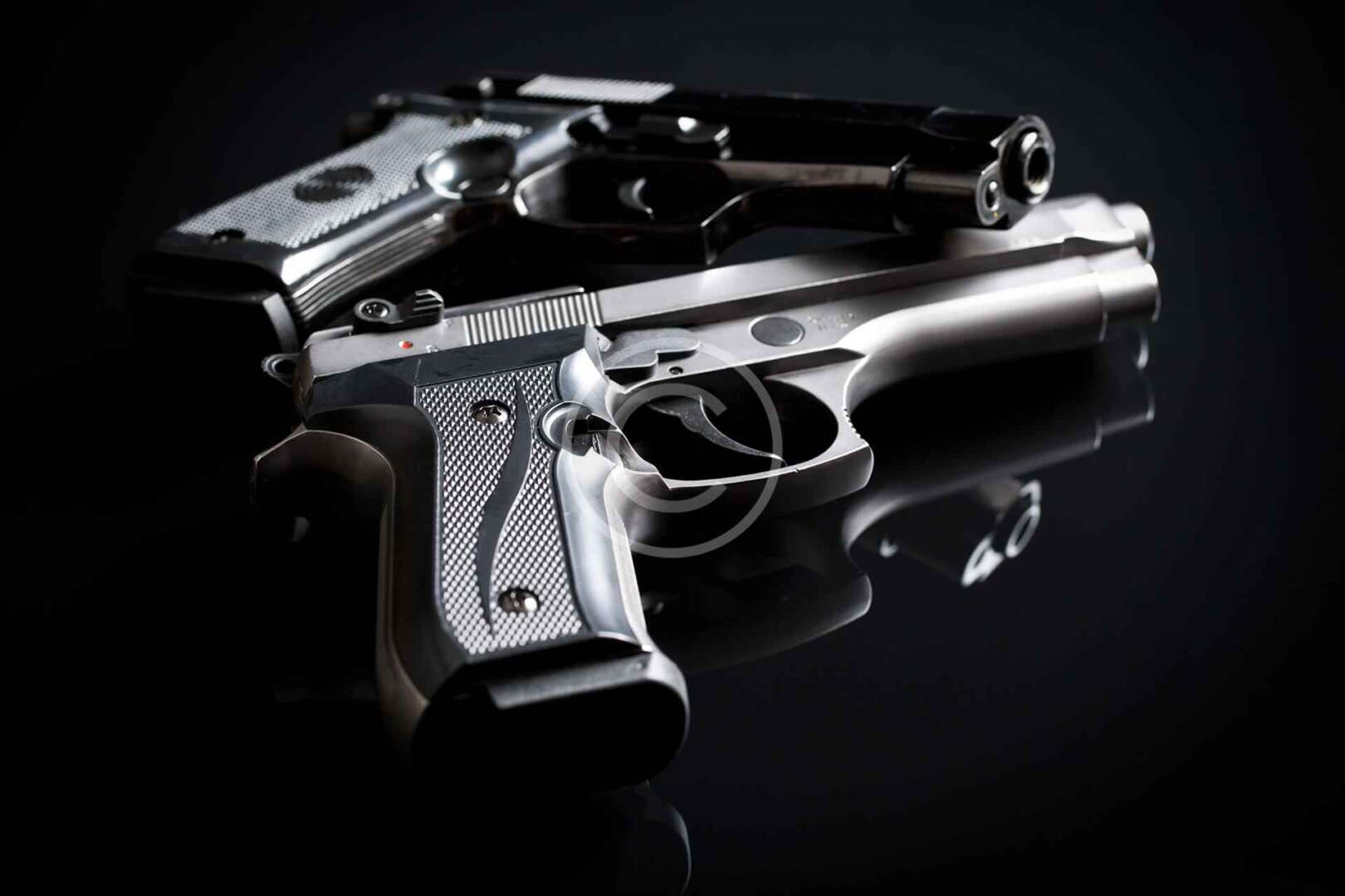 Two silver handguns on a black background.