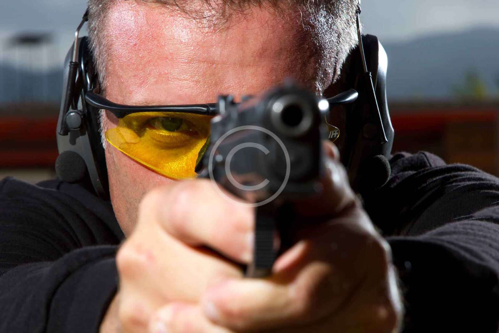 A man is holding a gun and aiming at a target.