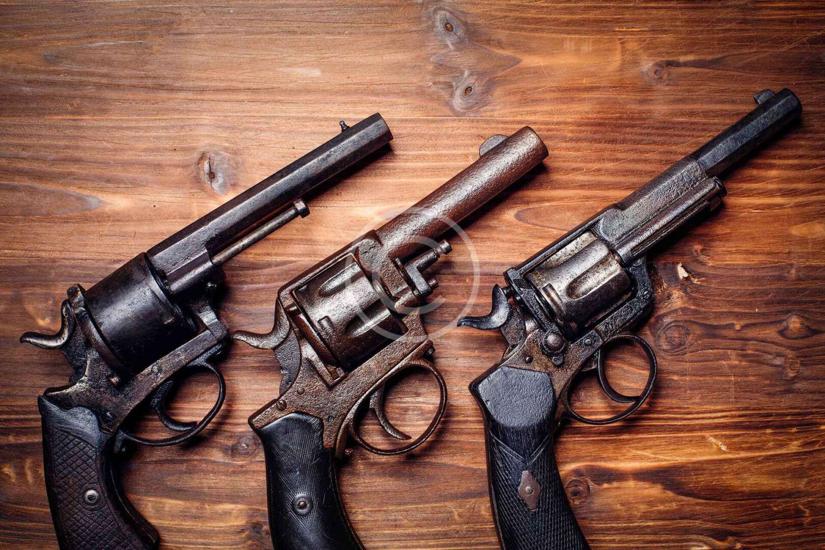 Three revolvers on a wooden table.
