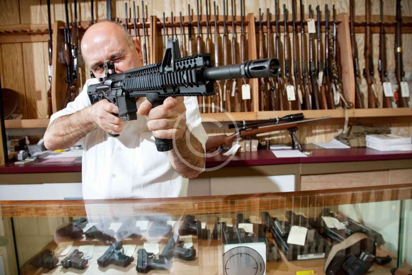 A man is holding a gun in a gun store.